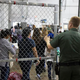 In this photo, provided by U.S. Customs and Border Protection, a U.S. Border Patrol agent watches as people taken into custody in cases related to illegal entry into the United States, stand in line at a facility in McAllen, Texas, on June 17.